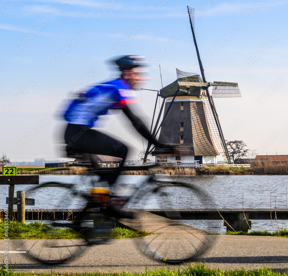 Obraz premium Purposely blurred cyclist and a windmill in the Netherlands