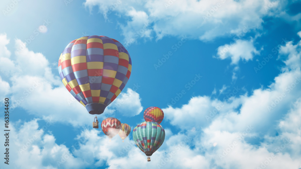 Fototapeta premium Mehrere Heißluftballons fliegen vor einem blauen bewölkten Himmel bei Sonnenuntergang 