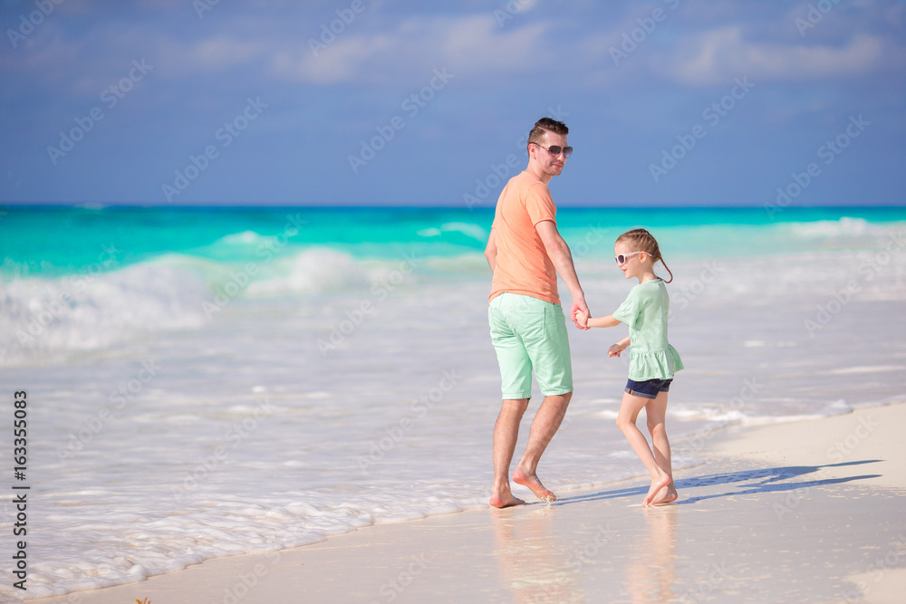 Little adorable girl and young father at tropical white beach. Family beach vacation Little adorable girl and young father at tropical white beach. Family beach vacation