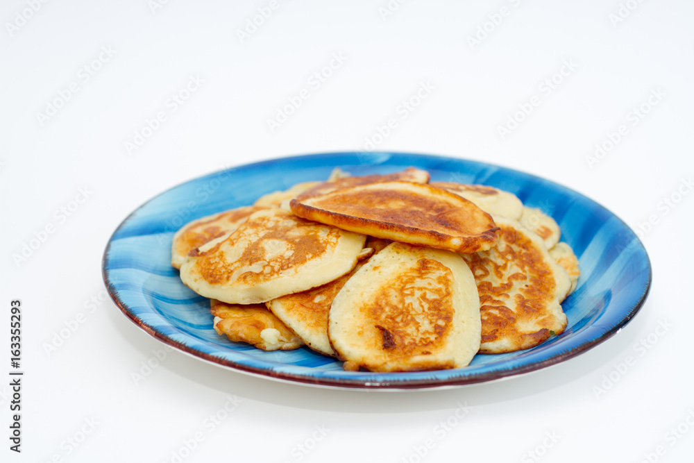 Ruddy freshly cooked pancakes lie on a blue plate on a white background. Ruddy freshly cooked pancakes lie on a blue plate on a white background.