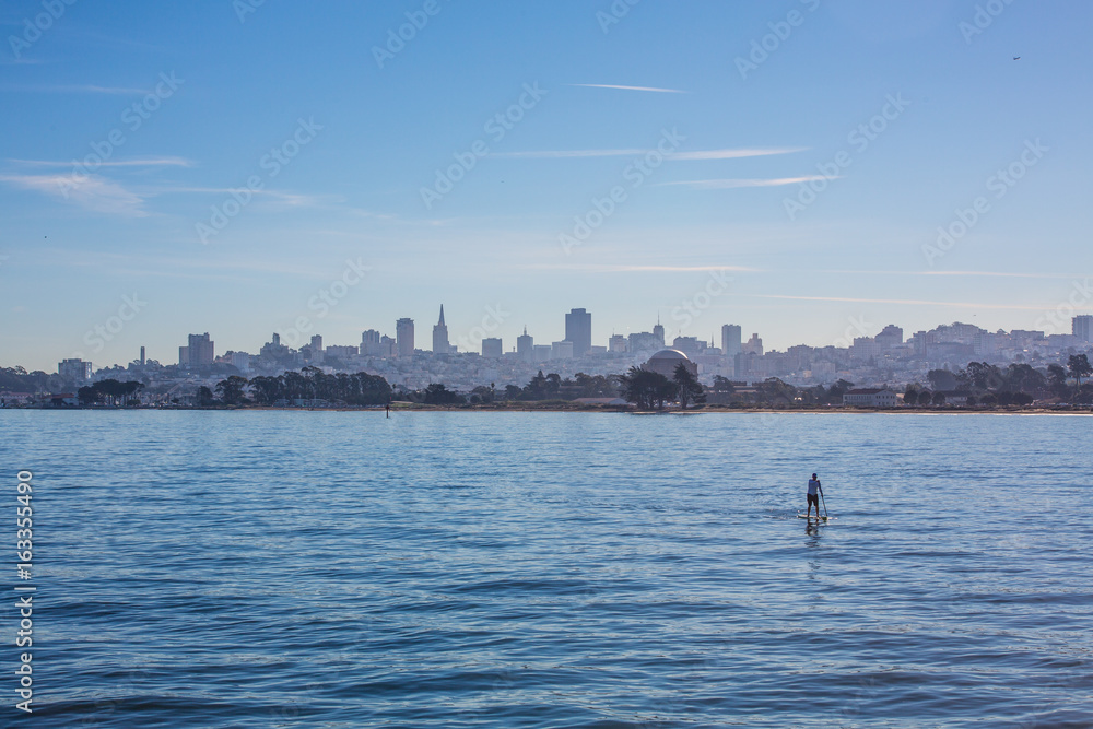 A paddle boarder against the Sam Francisco skyline