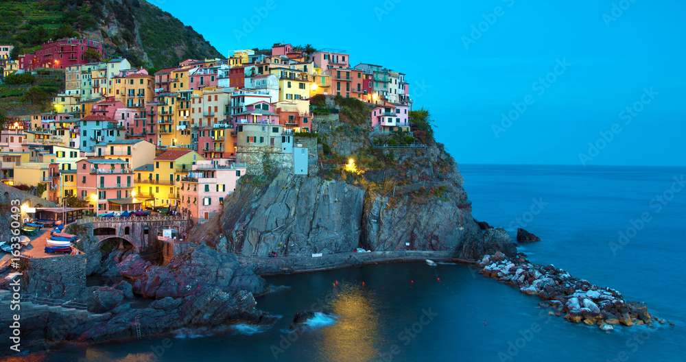 Magical beautiful landscape with bright colored houses on the rock on the sea coast of Manarola in Cinque Terre, Liguria, Italy, Europe in the evening
