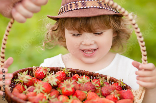 Adorable little girl with the basket full of stawberry