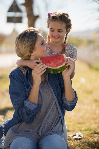 Mother and daughter having watermelon slice in park