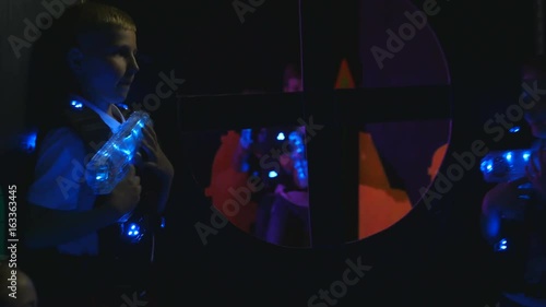 One group of children hide from another group of children plaing lasertag