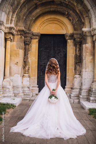 Beautiful bride outdoors. Beautiful bride with bouquet of flowers outdoor . Beautiful bride posing in her wedding day. Wedding bride near church.