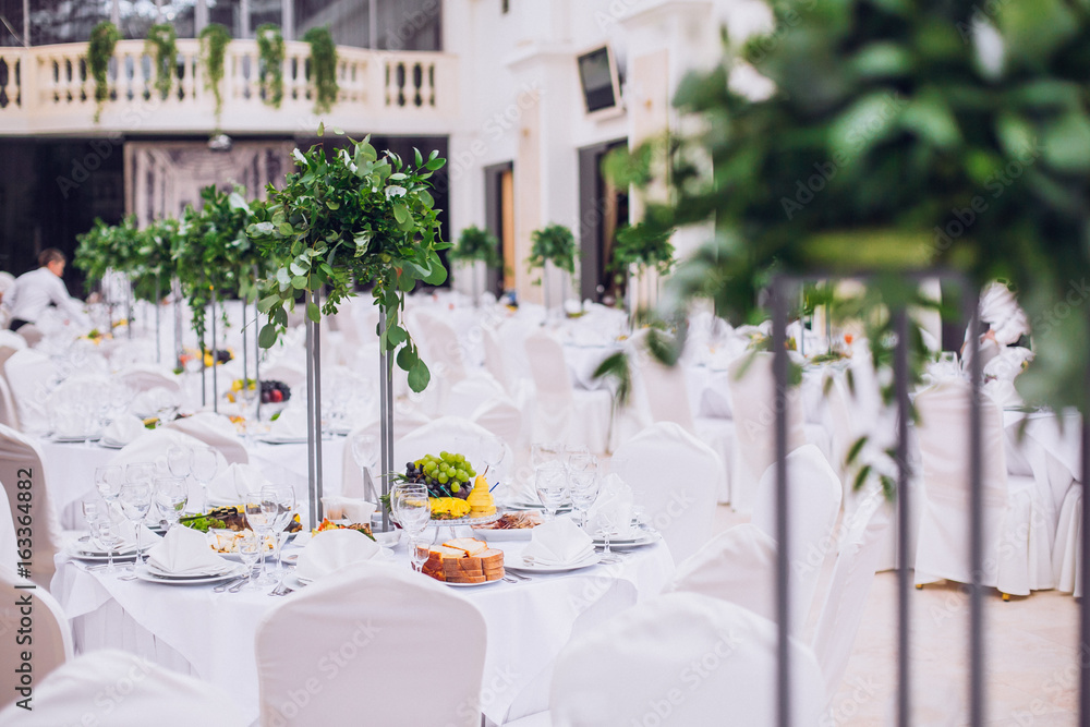 Fototapeta premium Catering in restaurant. Wedding banquet. Wedding party. Restaurant event. Banquet, wedding, catering, celebration. Wedding restaurant. Served tables. Decor in green and white colors.