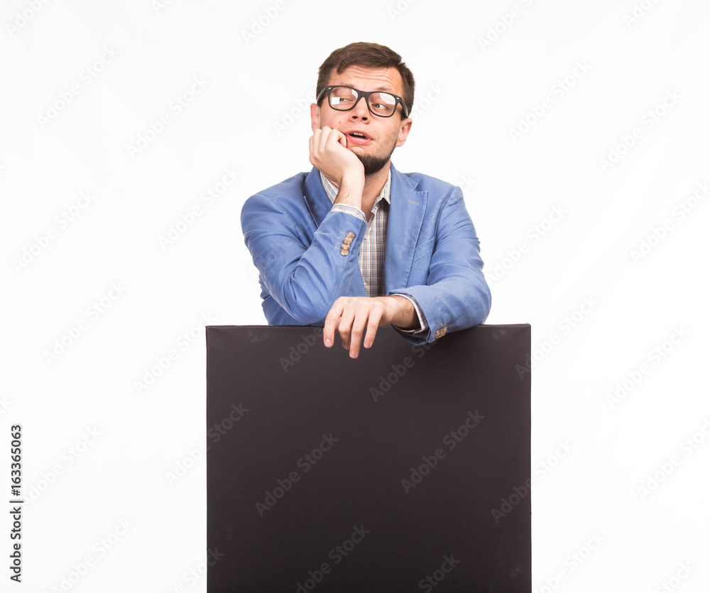 Young pensive man portrait of a confident businessman showing presentation, pointing paper placard gray background. Ideal for banners, registration forms, presentation, landings, presenting concept. Young pensive man portrait of a confident businessman showing presentation, pointing paper placard gray background. Ideal for banners, registration forms, presentation, landings, presenting concept.