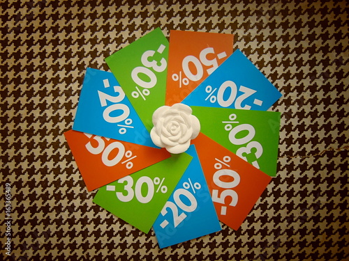 summer sale price tags 50%, 30% and 20% in a circle around white flower