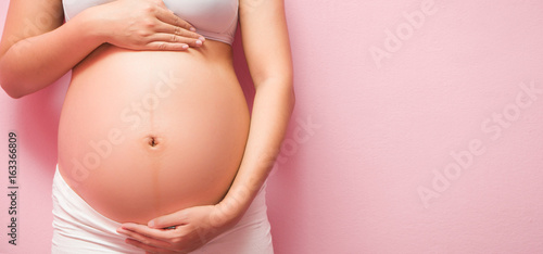 Close up of pregnant belly.on pink background