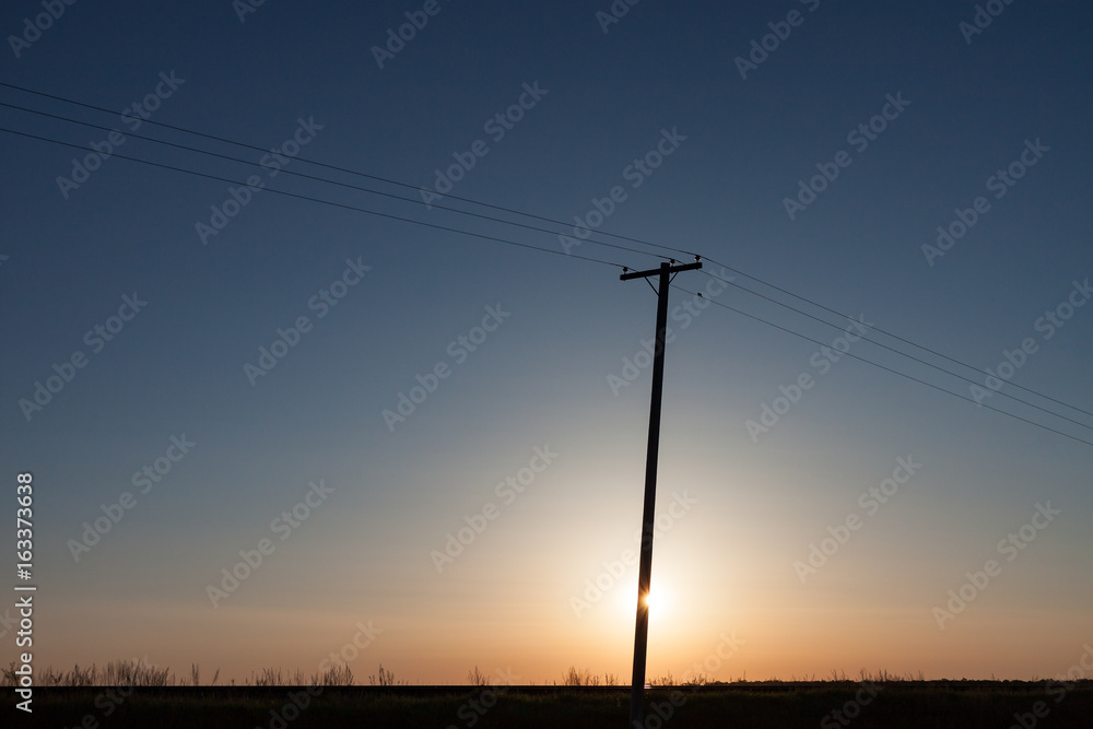 Silhouetted Power Pole On Canadian Prairie At Sunrise