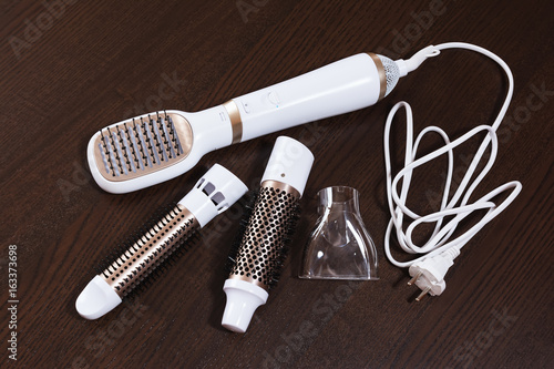 Hair styling set with straightener and curling accessories on wooden background.