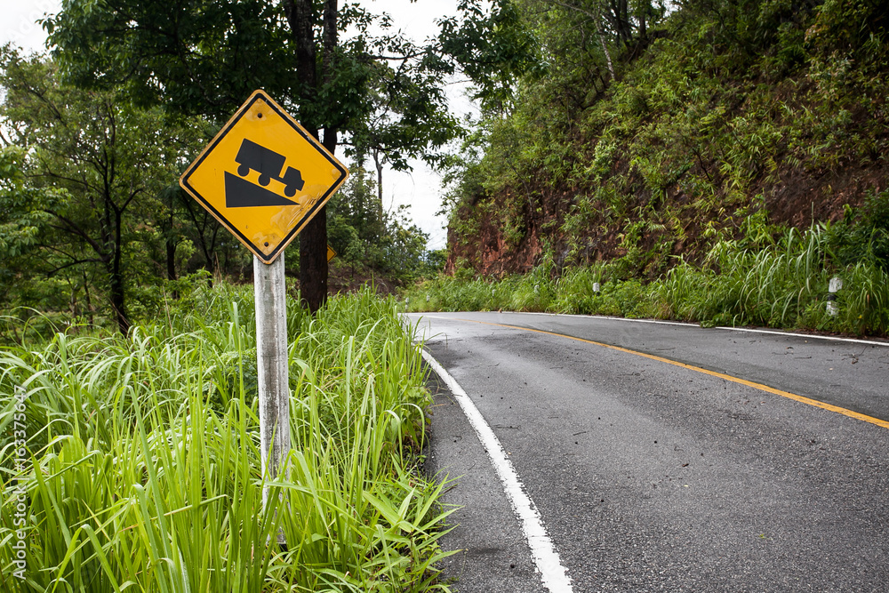 The street sign down hill warning on the mountain road The street sign down hill warning on the mountain road