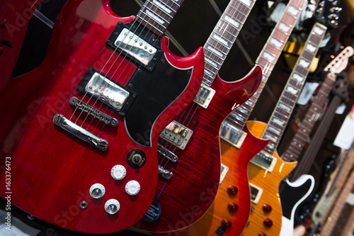 Many electric guitars hanging on wall in the shop