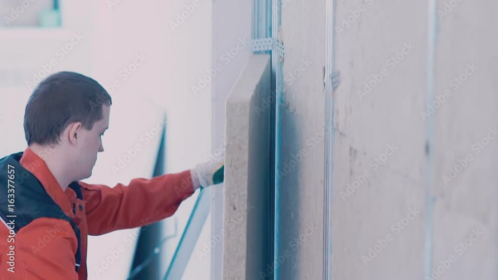 Worker lays a insulator in the walls close up Worker lays a insulator in the walls close up