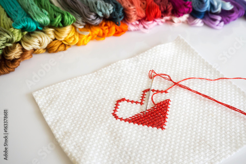 Fototapeta Naklejka Na Ścianę i Meble -  Stitching red heart shape on white fabric on white background.