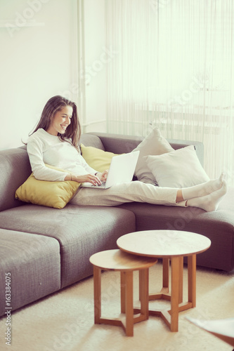 Young woman in living room surfing the internet