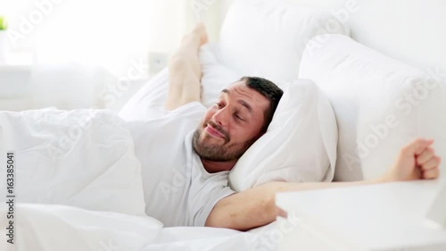 man waking up in bed at home