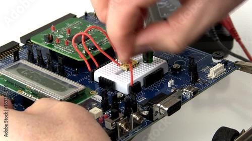 An engineer creates a prototype circuit by wiring components in breadboard area of development board. This clip is time-lapse  photo