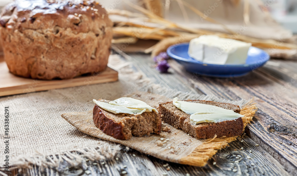 A loaf of bread and pieces of bread and butter on a wooden table A loaf of bread and pieces of bread and butter on a wooden table