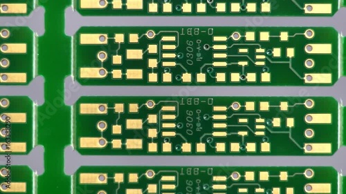 A palette of bare circuit boards rotates on end from left to right revealing traces, component pads and through holes. photo