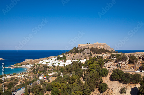 Fototapeta Naklejka Na Ścianę i Meble -  Lindos town at the foot of the mountain. Acropolis of Lindos is located on a hill above the town. Bay and harbor with beach.