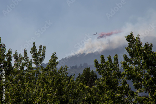 Wall Mural Plane dropping red slurry fire retardant on a forest fire in Durango, Colorado