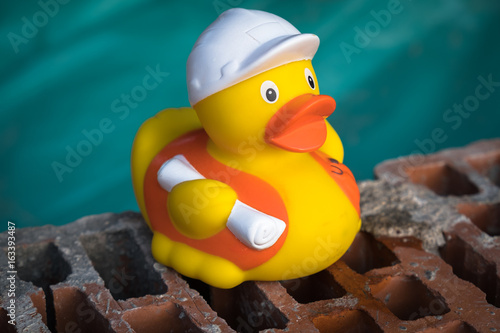 Rubber toy duck construction worker sitting on a building block