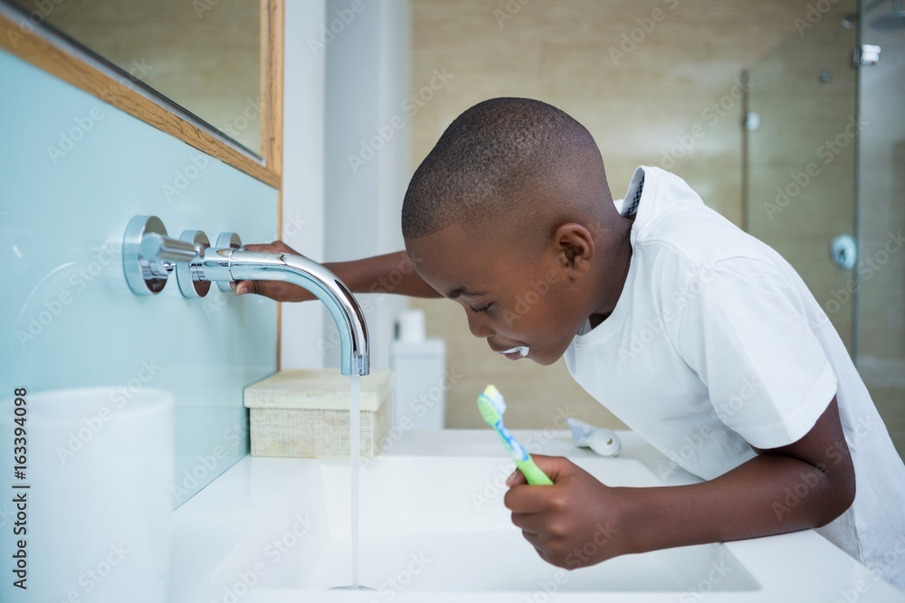 Side view of boy spitting while holding brush in sink Side view of boy spitting while holding brush in sink