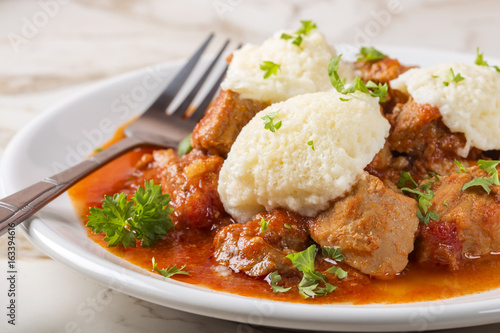 Goulash with dumplings on plate with fork