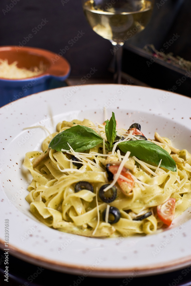 Traditional italian cuisine. Pasta with cjicken slices and mozarella cheese. Glass of wine.