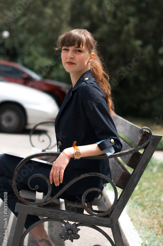 Business lady in a business suit sits on a bench.