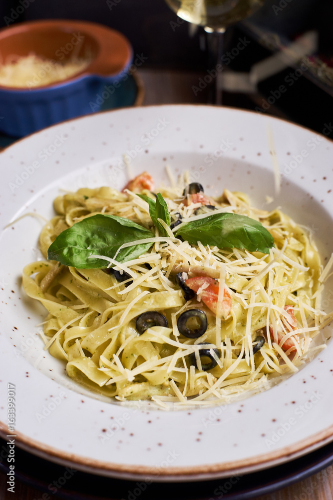 Closeup view of plate with traditional italian pasta with chiken and cheese. Glass of wine.