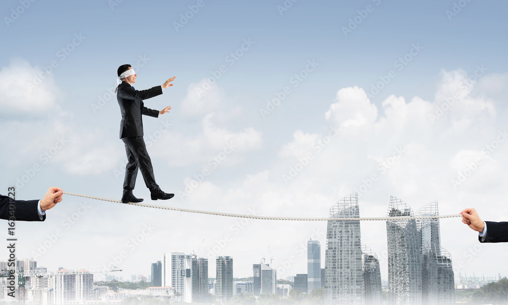 Business concept of risk support and assistance with man balancing on rope Business concept of risk support and assistance with man balancing on rope