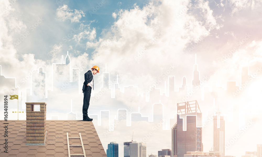 Engineer man standing on roof and looking down. Mixed media Engineer man standing on roof and looking down. Mixed media