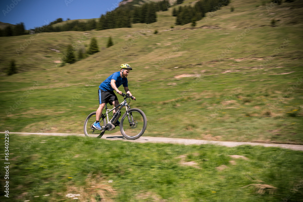 Junger Mann fährt mit E-Mountainbike in den Bergen