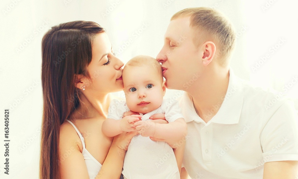 Portrait closeup happy family, mother and father kissing baby Portrait closeup happy family, mother and father kissing baby