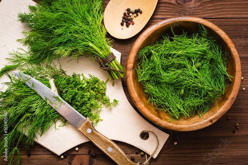 Chopped fresh dill on a cutting board and dill in a wooden bowl on the table Fototapet
