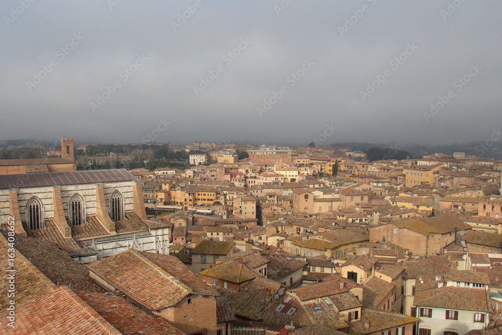 Cityscape of Siena with thick fog on background. Tuscany, Italy.