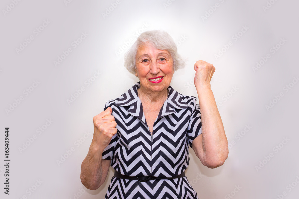 The portrait of a cheerful senior woman gesturing victory over pink The portrait of a cheerful senior woman gesturing victory over pink