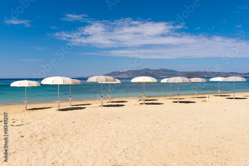 White parasols on Idyllic tropical beach with sand  turquoise sea water and blue sky. Naxos island. Cyclades  Greece. 