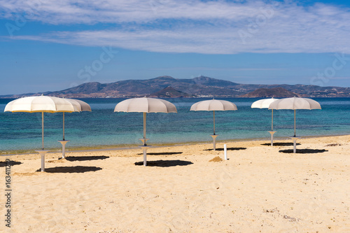 White parasols on Idyllic tropical beach with sand  turquoise sea water and blue sky. Naxos island. Cyclades  Greece. 