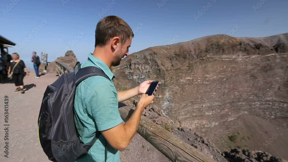 Excited man coming to observation deck edge on Vesuvius top take video of crater Excited man coming to observation deck edge on Vesuvius top take video of crater