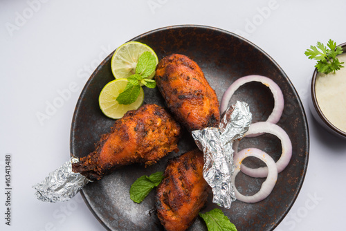 Chicken Tangri kabab or kebab - three Chicken leg pieces marinated with red sauce then grilled and served with salad. It can be served with green chutney photo