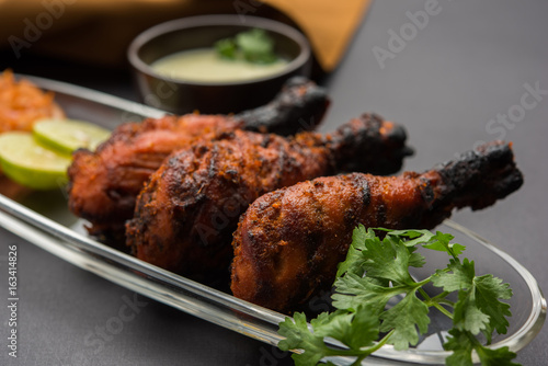 Chicken Tangri kabab or kebab - three Chicken leg pieces marinated with red sauce then grilled and served with salad. It can be served with green chutney photo