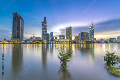 Ho Chi Minh City, Vietnam - June 15th, 2017: Riverside City sunrays clouds in the sky at end of day brighter coal sparkling skyscrapers along beautiful river in Ho Chi Minh City, Vietnam