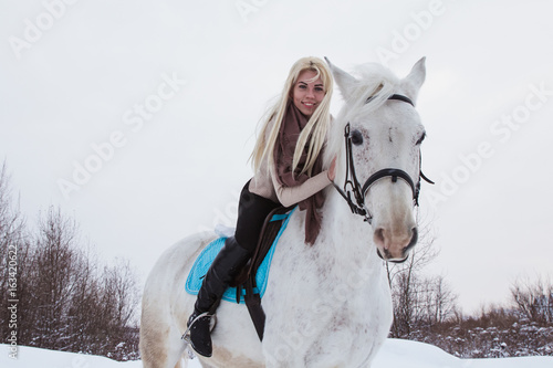 Nice girl and white horse outdoor in a winter