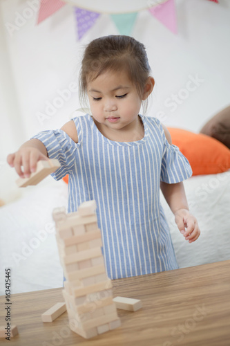 Happy little Asian girl playing with wooden blocks