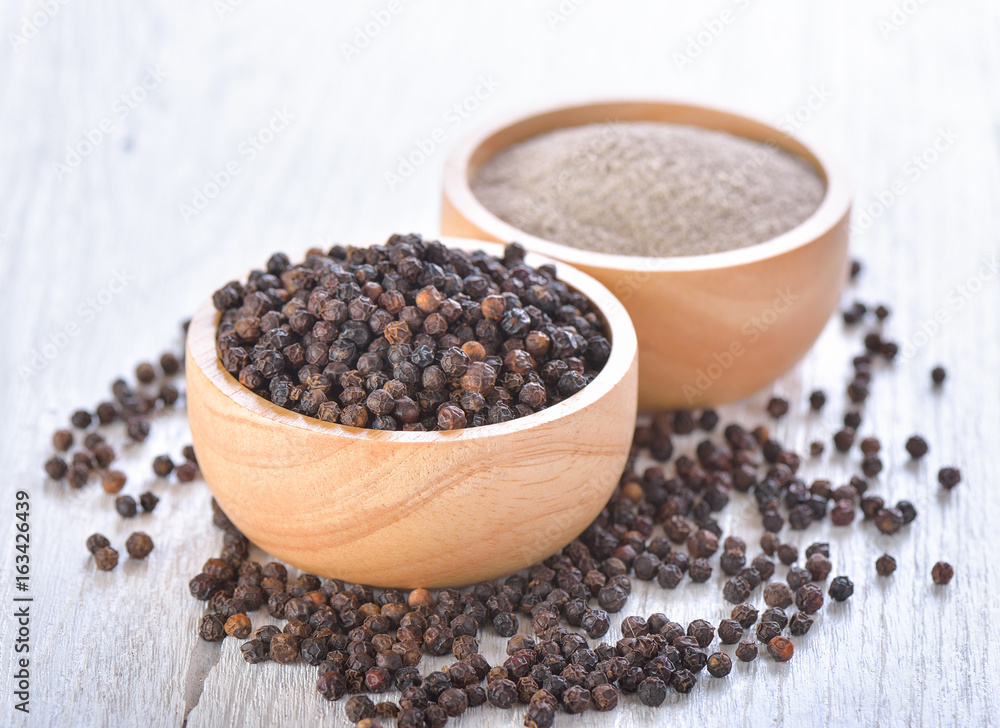 Black peppercorns powder on white wooden Black peppercorns powder on white wooden