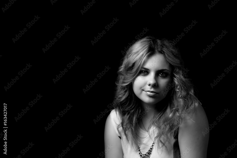 Black and white low key portrait of attractive long hair young woman looking forward and smiling. Black and white low key portrait of attractive long hair young woman looking forward and smiling.